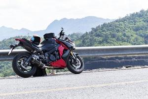 estilo moderno de motocicleta roja estacionada en la carretera con fondo de vista a la montaña y espacio de copia