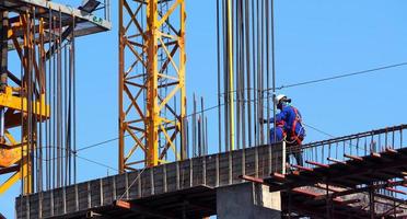 obra de construcción y trabajador de pie sobre material de acero y hormigón y cielo azul. foto