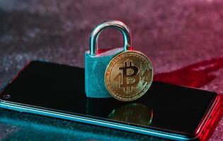 Bitcoin coin and a padlock on a smartphone. photo