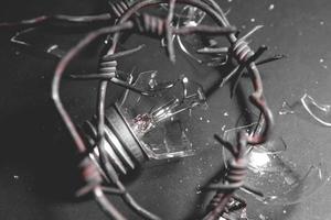 Broken electric light bulb with barbed wire. Concept of electricity prices and the electricity crisis in World photo