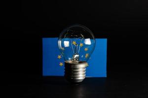 bombilla rota con bandera europea sobre fondo negro. concepto de precios de la electricidad y la crisis de la electricidad en europa foto