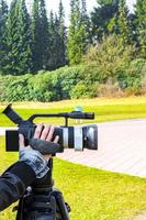 Woman girl filming in the park with a professional camera. photo