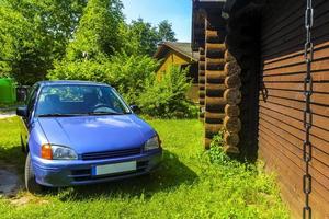 Brown wooden cottage house in nature with blue parked car. photo