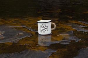 Close up tourist mug in shallow river concept photo