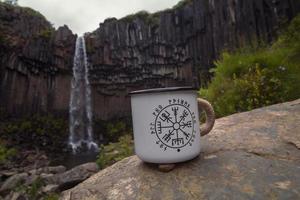 Close up mug on rock against waterfall concept photo