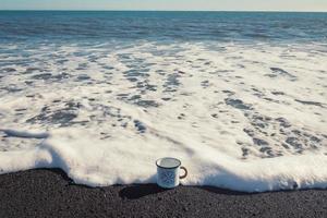 Close up enamel cup on sea surfline concept photo