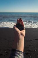 Close up woman holding pile of black sand on beach concept photo