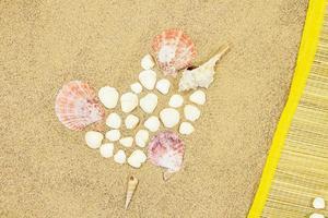 corazón de caracola y conchas blancas, tumbona de paja sobre arena. día de san valentín, viajes, vacaciones foto