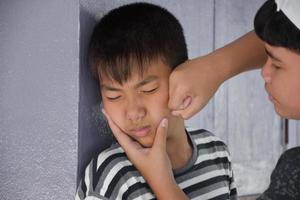 Asian secondary school boy was intimidated by bad habit students at the wall of the bathroom, soft and selecitve focus, bad habit students and teenagers concept. photo
