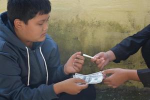 Boy learning to smoke by himself in the area behind the school fence which is a hidden place for people, bad influence of secondary school or junior high school life, addiction. photo