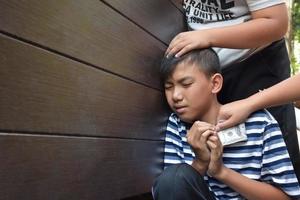 Asian secondary school boy was intimidated by bad habit students at the wall of the bathroom, soft and selecitve focus, bad habit students and teenagers concept. photo