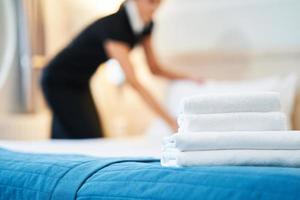 Maid making bed in hotel room photo