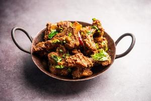 carne de cordero o pollo sukha, murgh picante seco o carne de cabra servida en un plato o bol foto