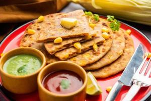 paratha o parotha rellenos de maíz dulce servidos en un plato, receta de pan plano indio hecha relleno makai foto