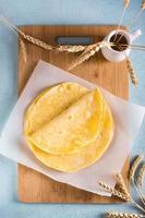 pila de tortillas de maíz mexicanas planas en tablero de madera en la mesa. vista superior y vertical foto