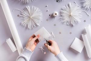 las manos de los niños con tijeras cortan un copo de nieve navideño de papel. decoración hecha a mano