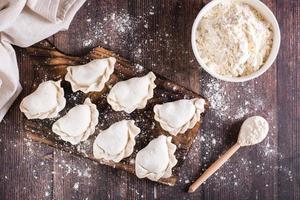 Raw dumplings on a cutting board and flour on the table. Home cooked food. Top view photo