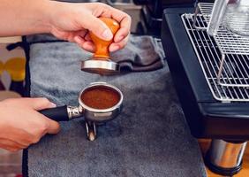 café barista haciendo café con prensas manuales café molido usando tamper en la barra de mostrador de madera en la cafetería foto