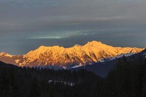 Snow covered mountain top is illuminated by unending sun photo