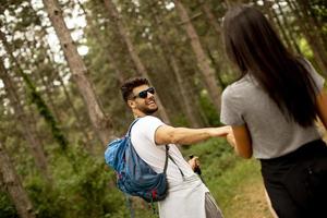 Smiling young couple walking with backpacks in the forest photo