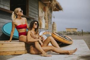 Young women in bikini sitting by the surf cabin on a beach at summer day photo