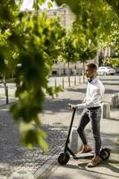 Young African American using electric scooter and waiting to cross the street photo