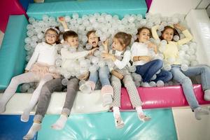 Happy little kids in ball pit smiling happily at camera while having fun photo