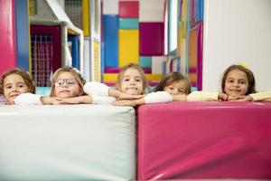 Group of cute little girls hiding behind large leather blocks photo