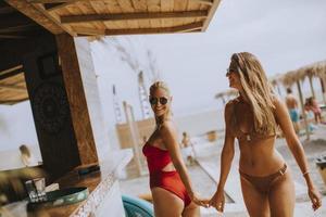 Young women in bikini walking by the surf cabin on a beach at summer day photo