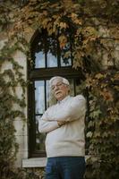 Senior man standing by the window at the autumn day photo