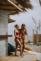 Young women in bikini standing by the surf cabin on a beach at summer day photo