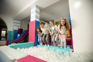 Happy little girls jumping into ball pit photo