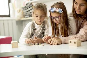 dos lindas niñas jugando con juguetes educativos preescolares con maestra de jardín de infantes foto