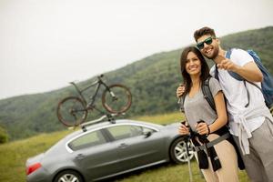 Smiling young couple walking with backpacks on the green hills photo