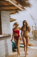 Young women in bikini walking by the surf cabin on a beach at summer day photo