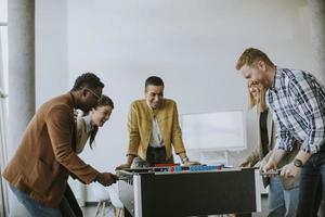 Young casual multiethnic business people playing table football and relaxing at office photo