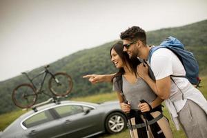 pareja joven sonriente caminando con mochilas en las verdes colinas foto