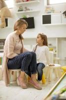 Nursery teacher talking to little girl with a problem in the kindergarten photo