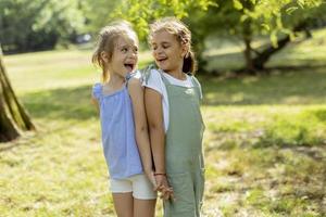 Two little girls standing back to back in the park photo