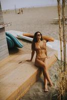 Young woman in bikini sitting on the beach at summer day photo