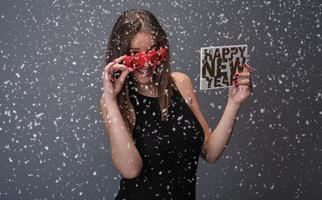 Beautiful woman celebrating New Year with confetti and champagne holding sign. isolated photo