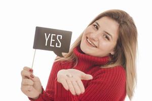 Woman holding engagement ring and sign saying YES photo