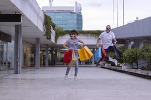 Portrait of cheerful Caucasian young couple man and woman holding many paper bags after shopping while walking and talking on street. Happy family couple with packages outdoor. Buying concept photo