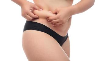 Midsection view of a woman pinching skin for fat test. Isolated on white background. photo