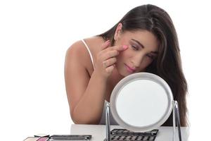 young woman checks her face skin in the mirror photo