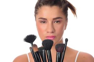 young girl posing with makeup brushes on a white background photo