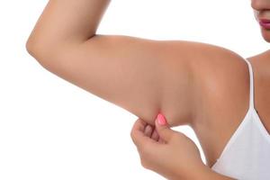 Woman pinching a fat on her arms on white background photo