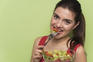 Portrait of a happy playful girl eating fresh salad from a bow photo