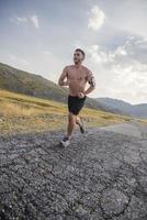 corredor de hombre deportivo corriendo en la meseta de la montaña en verano foto