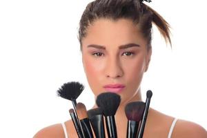 young girl posing with makeup brushes on a white background photo